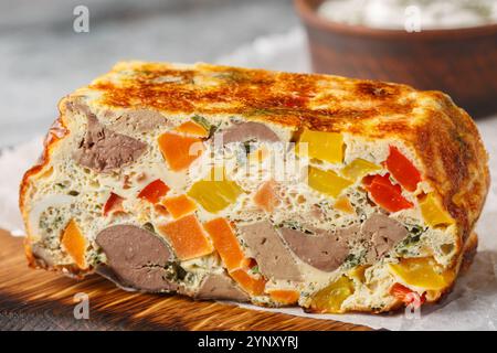 Cocotte de foie avec légumes, herbes et œufs gros plan sur une planche de bois sur la table. Horizontal Banque D'Images