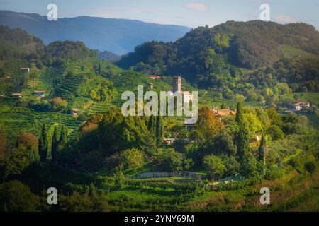 Collines de Prosecco, vignobles et église San Lorenzo au lever du soleil. Site UNESCO. Farra di Soligo. Région de Vénétie, Italie, Europe. Banque D'Images