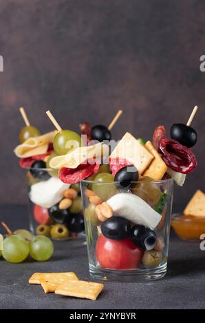 Jarcuterie en deux verres comprend différents types de saucisses, de cornichons, de fromage, de noix, de légumes et de fruits. Version moderne d'en-cas festifs Banque D'Images