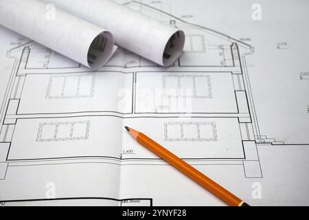 Dessins architecturaux montrant des plans de maison, accompagnés d'un crayon et de plans enroulés, symbolisant le processus de conception et de construction. Banque D'Images