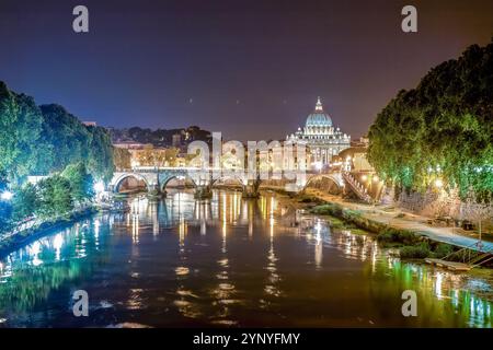 Le Tibre reflète les lumières de la ville tandis que la Cité du Vatican se dresse majestueusement la nuit à Rome, en Italie. Banque D'Images