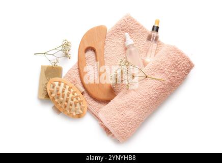 Composition avec outil de massage corporel guasha en bois, bouteilles de sérum et fleurs sur fond blanc Banque D'Images