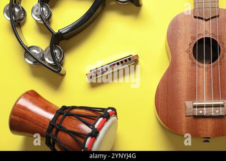 Harmonica, tambour, tambourin et ukulélé sur fond jaune Banque D'Images