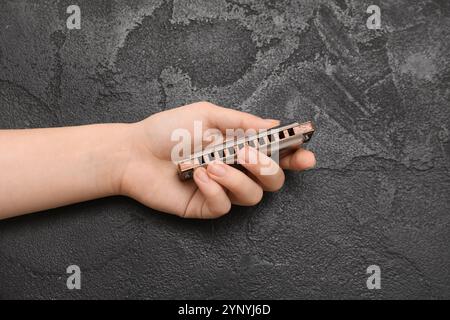 Main féminine avec harmonica sur fond sombre, gros plan Banque D'Images