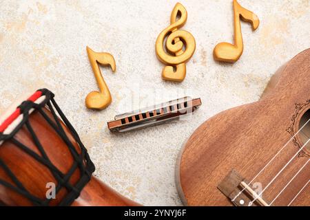 Harmonica, tambour, ukulélé et notes de musique sur fond clair Banque D'Images