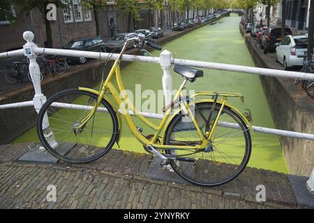 Vélo jaune garé sur un pont dans le centre de Delft Banque D'Images