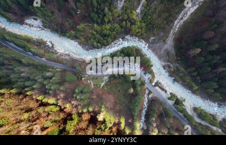 Rivière sinueuse coulant à travers la vallée de montagne avec des voitures garées près de la route en automne Banque D'Images