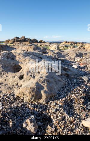 Gros plan d'un rocher sur une plage avec des galets Banque D'Images