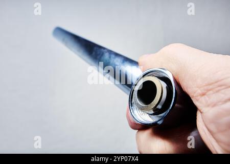 Robinet mélangeur à col long pivotant vertical le plus long du robinet dans la main du plombier sur fond gris clair. Banque D'Images