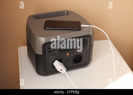 Recharge de smartphone à partir d'une station d'alimentation portable sur une table de nuit à l'intérieur Banque D'Images