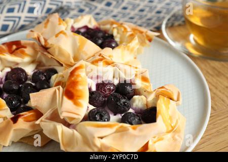 Délicieuses pâtisseries feuilletées avec des myrtilles et du thé sur une table en bois, gros plan Banque D'Images