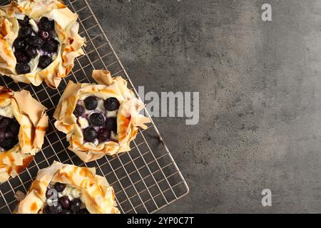 Délicieuses pâtisseries feuilletées aux myrtilles sur table texturée grise, vue de dessus. Espace pour le texte Banque D'Images