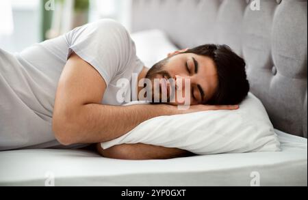 Sommeil confortable. Homme arabe millénaire qui dormait paisiblement et voit des rêves sucrées, allongé dans un lit confortable et un oreiller enrageant Banque D'Images