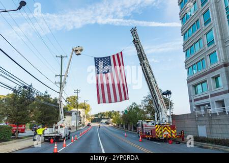 Drapeau américain suspendu à un camion de pompiers au-dessus d'une rue fermée en préparation pour la course de 5K, Conshohocken, PA États-Unis Banque D'Images