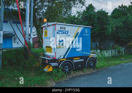 Balikpapan, Indonésie - 3 septembre 2024. Un transformateur mobile stationné dans une zone résidentielle, alimentant les maisons environnantes. Banque D'Images