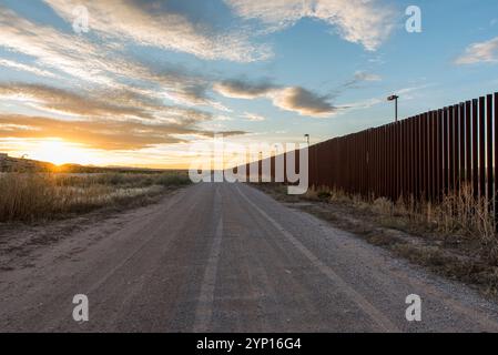Route de terre rustique par long United States, barrière frontalière du Mexique au coucher du soleil avec ciel coloré Banque D'Images