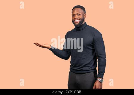 Jeune homme d'affaires afro-américain montrant quelque chose sur la paume de sa main tout en souriant à la caméra Banque D'Images