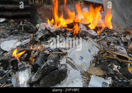 Laguna, Philippines. 28 nov 2024 : incendie de déchets et d'E-déchets dans la cour d'une maison. Beaucoup de Philippins brûlent des ordures dans les arrière-cours, près de la route ou de la forêt. La loi interdit ce brûlage à ciel ouvert, mais la pratique polluante et nocive appelée «pagsisiga» est répandue dans les zones rurales. Fumées et résidus de combustion des déchets ménagers, électroniques, plastiques, synthétiques, produits chimiques, le carton, les matières organiques polluent l'environnement, les eaux souterraines et l'air. La 5ème session du Comité intergouvernemental de négociation sur la pollution plastique (CNI-5) se tient cette semaine en Corée du Sud. Crédit : Kevin Izorce/Alamy Live News Banque D'Images