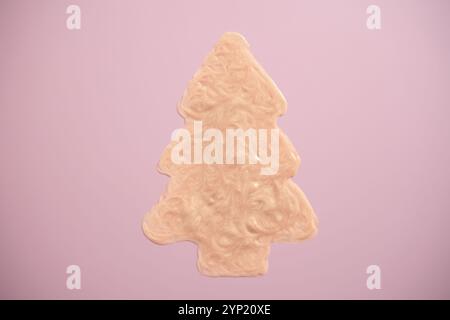 Crème beige scintillante en forme de sapin de Noël sur fond rose. Maquillage et soins corporels des fêtes Banque D'Images