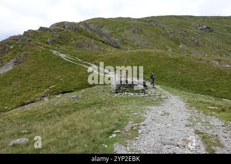 Homme marchant près du refuge en pierre de Nan Bield Pass jusqu'au Wainwright « Harter Fell » de « Mardale Ill Bell » dans le parc national du Lake District, Cumbria. Banque D'Images