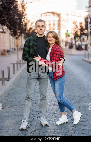 Célébrer l'amour : un couple élégant embrasse la joie de l'ensemble dans une charmante rue de la ville. Banque D'Images