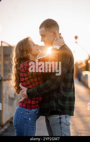 Coucher de soleil romantique étreinte d'un couple dans des chemises en flanelle. Banque D'Images