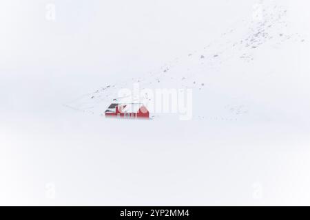 Un rorbu rouge dans la neige à Skagsanden Beach, Flakstad, Flakstadoya, Nordland, Lofoten, Norvège, Europe Banque D'Images