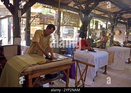 Travailleurs appliquant de la cire-resist à l'aide d'un tampon de plaque de cuivre (capuchon), atelier de batik Wirakuto, Pekalongan, île de Java, Indonésie, Asie du Sud-est, Asie Banque D'Images