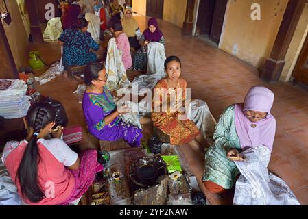 Femmes utilisant un outil semblable à un stylo (canting) pour appliquer de la cire chaude liquide dans le processus de fabrication du batik, atelier de batik Wirakuto, Pekalongan, île de Java, Indonésie Banque D'Images