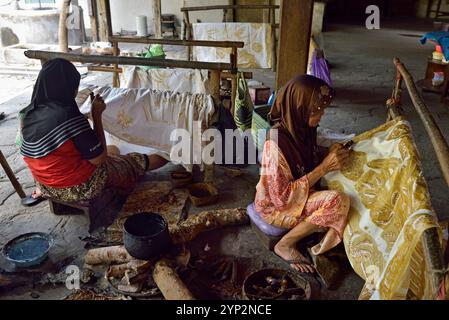 Femmes utilisant un outil semblable à un stylo (canting) pour appliquer de la cire chaude liquide pour créer un motif sur le tissu sans dessin préliminaire, Nyah Kiok batik maison Banque D'Images