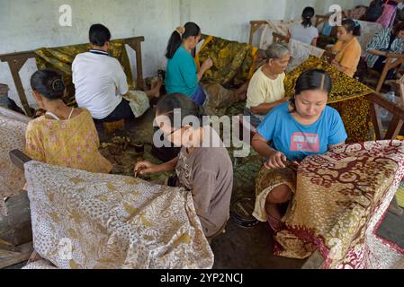 Femmes utilisant un outil en forme de stylo (canting), pour appliquer de la cire chaude liquide pour créer un motif sur le tissu avant la teinture, atelier de Kidang Mas Batik House Banque D'Images