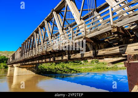 Un pont sur une rivière avec un ciel bleu en arrière-plan. Le pont est vieux et en bois Banque D'Images