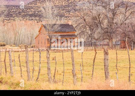 Une ferme rustique se trouve dans un champ avec une clôture autour d'elle. La maison est entourée d'une clôture et de quelques arbres. La scène est paisible et sereine, avec Banque D'Images