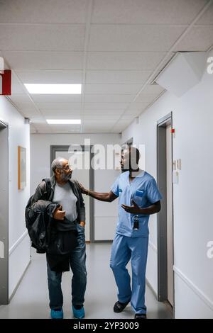 Médecin masculin consolant et parlant avec un homme âgé dans le couloir de l'hôpital Banque D'Images