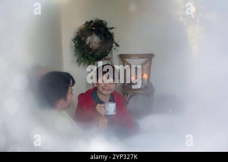 23 novembre 2024 : image symbolique de l'anticipation de Noël à la maison : prise à travers une vitre glacée, la photo montre un père et son fils jouissant ensemble du cacao. Un aperçu de la joie des petits moments alors que l'hiver s'installe à l'extérieur. *** Symbolbild für heimische Weihnachtsvorfreude : durch eine vereiste Scheibe aufgenommen zeigt das Bild Vater und Sohn beim gemeinsamen Genuss von Kakao. Ein Einblick in die Freude kleiner Momente, während draußen der Winter Einzug hält. Banque D'Images