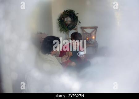 23 novembre 2024 : image symbolique de la pleine conscience pendant l'Avent : photographiée à travers une fenêtre glacée, la photo montre un père et son fils en train de faire une pause ensemble. Une invitation à faire une pause dans l'agitation d'avant Noël et profiter de petits moments de joie. *** Symbolbild für Achtsamkeit im Advent : durch eine vereiste Scheibe fotografiert, zeigt das Bild Vater und Sohn BEI einer gemeinsamen Pause. Eine Einladung, im vorweihnachtlichen Trubel innezuhalten und kleine Momente der Freude zu genießen. Banque D'Images