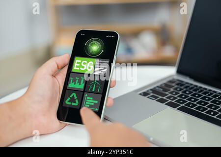 Main à l'aide d'ordinateurs portables pour analyser ESG sur l'écran de smartphone dans le concept de stratégie d'investissement d'entreprise, environnement social gouvernance investissement affaires conc Banque D'Images