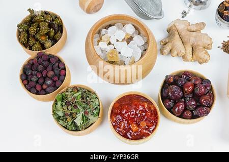 thé pour la santé, thé au gingembre, lin, herbe, cônes, aubépine, canina-rose sur une table blanche, place pour le texte, vue de dessus Banque D'Images