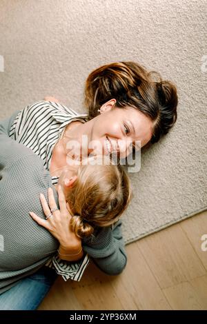 Directement au-dessus du plan de mère souriante embrassant son fils tout en étant allongé sur la moquette à la maison Banque D'Images