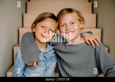 Garçon souriant avec le bras autour de frère à la maison Banque D'Images