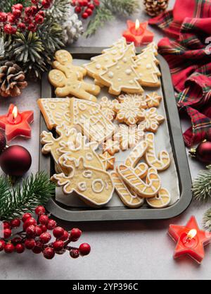 Plat de biscuits de pain d'épices de noël sur une plaque de cuisson, entouré de décorations festives et de bougies allumées, créant un SC de vacances chaleureux et accueillant Banque D'Images