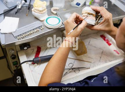 Vue détaillée d'un technicien dentaire restaurant un moule dentaire à l'établi. Banque D'Images