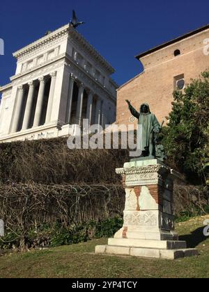 Une statue de bronze se dresse bien en vue devant un grand bâtiment classique sous un ciel bleu clair. Une végétation luxuriante encadre la scène, mettant en valeur le ri Banque D'Images