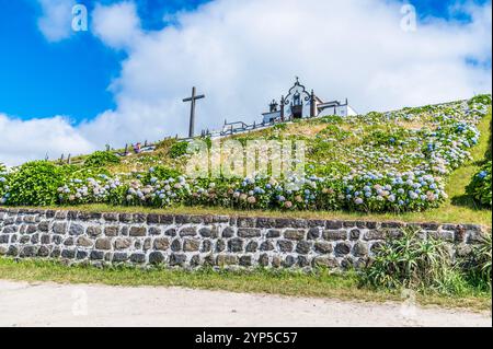 Une vue devant les hortensias regardant vers la chapelle de notre Dame de la paix à travers Ribeira Seca sur l'île de San Miguel dans les Açores en été Banque D'Images