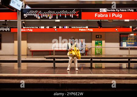 Barcelone-Espagne, 28 novembre 2024. Un banlieue est assis patiemment à la station de métro de Barcelone, reflétant le rythme quotidien de la vie urbaine Banque D'Images