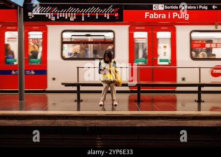 Barcelone-Espagne, 28 novembre 2024. Un utilisateur s'assoit tranquillement sur la plate-forme du métro, le train se précipitant, capturant l'essence de la vie urbaine à Barcelone Banque D'Images