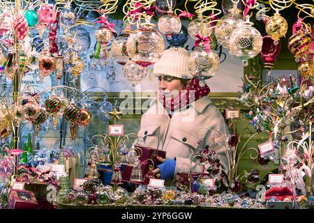 Bath, Royaume-Uni, 28 novembre 2024. Un support de stalle est photographié alors qu'elle parle aux clients le jour de l'ouverture du marché de Noël de Bath. Chaque année, les rues entourant les thermes romains et l'abbaye de Bath abritent plus de 220 stands remplis de cadeaux de Noël. Le marché de noël primé attire des acheteurs de toute l'Europe. Crédit : Lynchpics/Alamy Live News Banque D'Images