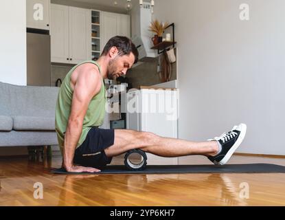 Homme caucasien effectuant des exercices de libération musculaire en utilisant le rouleau de mousse à la maison. Banque D'Images