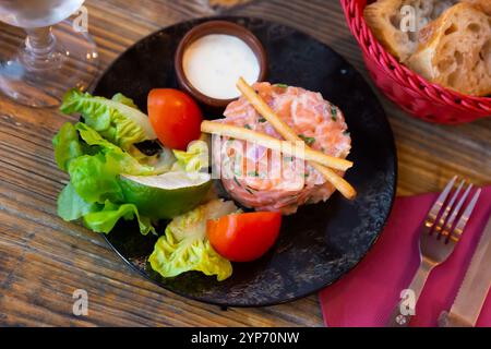 Tartare de saumon avec sauce crémeuse à la ciboulette, légumes, citron vert et gressins Banque D'Images