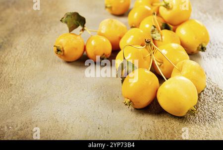 Petites pommes jaunes, variété chinoise, dispersées sur la table, vue de dessus, pas de gens Banque D'Images
